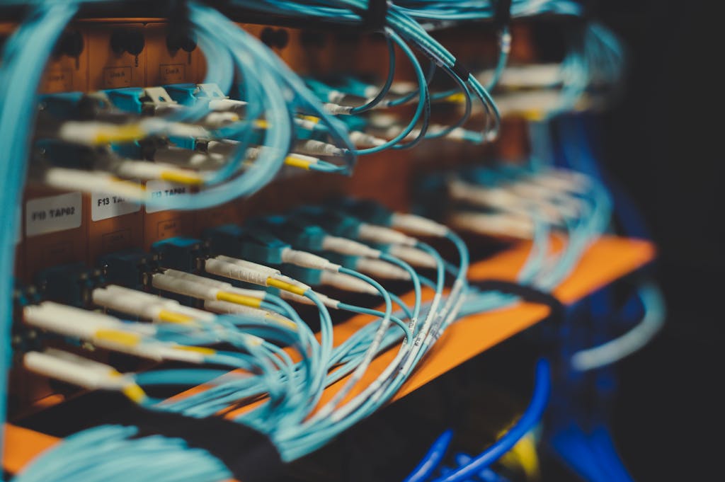 Closeup of many cables with blue wires plugged in modern switch with similar adapters on blurred background in modern studio